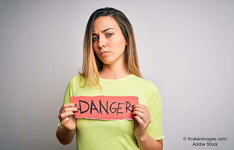 Eine Frau hält ein Schild mit der Aufschrift Danger. Foto: Krakenimages.com/Adobe Stock