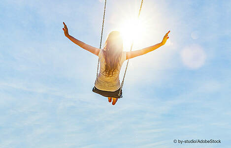 Ein junges Mädchen schaukelt der Sonne entgegen. Foto: by-studio/Adobe Stock