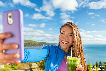 Ein Mädchen mit einem Smoothie in der Hand macht ein Selfie. Foto: Maridav/AdobeStock