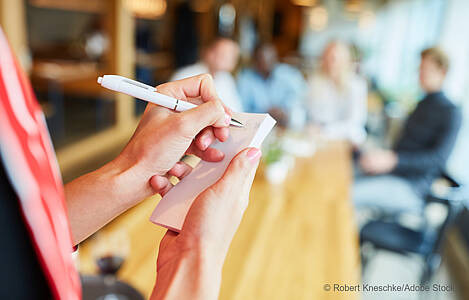 Der Arm einer Kellnerin mit einem Block in der Hand. Foto: Robert Kneschke/Adobe Stock.